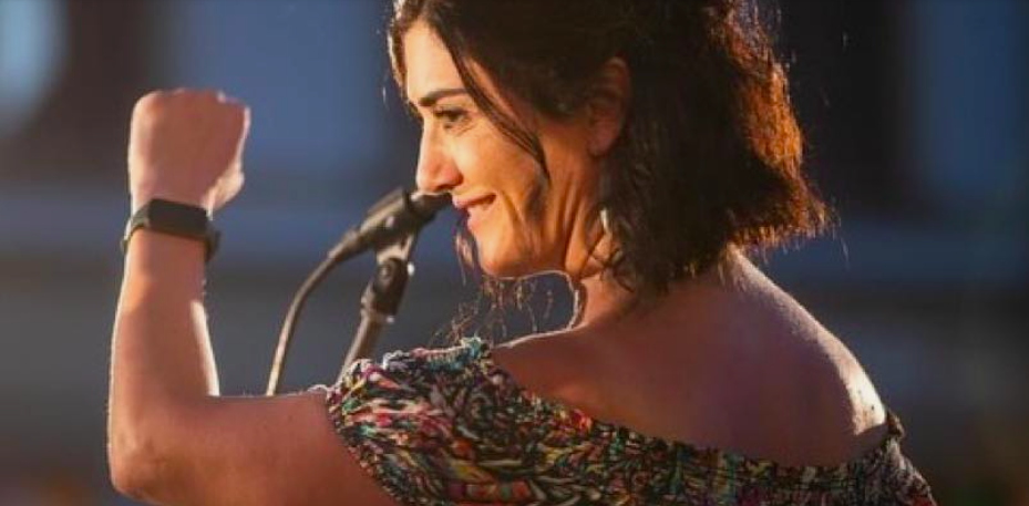 Young woman in profile standing at a microphone, shot from behind,